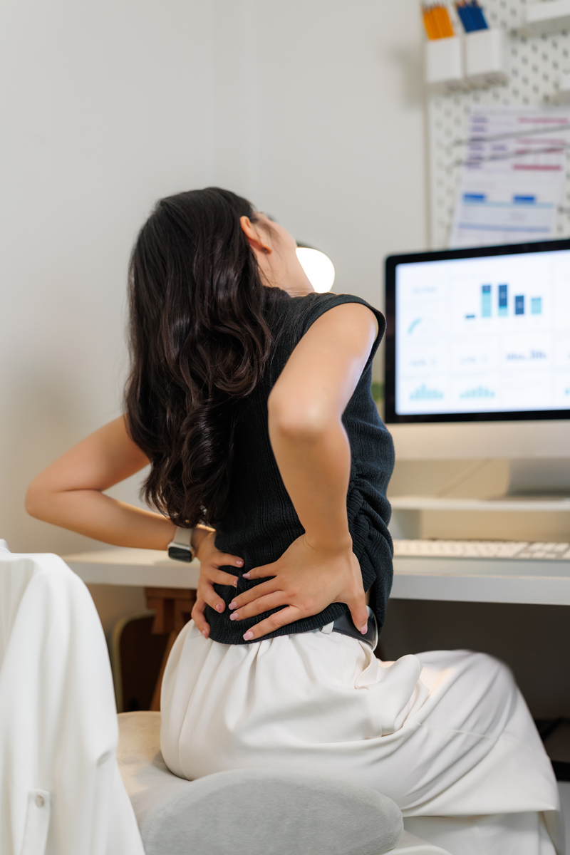 office worker suffering from back pain while working on computer